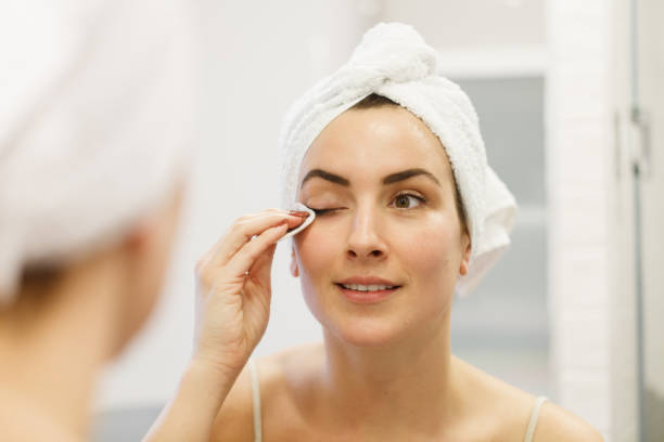 a woman removing makeup with a cotton pad